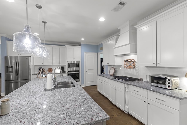 kitchen featuring appliances with stainless steel finishes, white cabinets, a kitchen island with sink, and sink