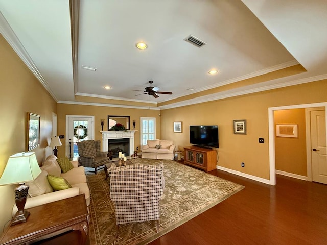 living room with a tray ceiling, crown molding, ceiling fan, and dark hardwood / wood-style floors