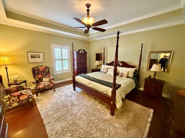 bedroom with a tray ceiling, ceiling fan, crown molding, and dark wood-type flooring