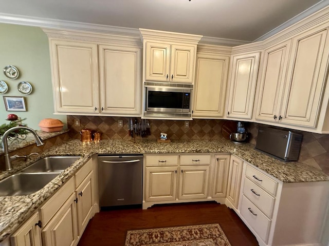 kitchen featuring tasteful backsplash, light stone counters, stainless steel appliances, sink, and cream cabinets