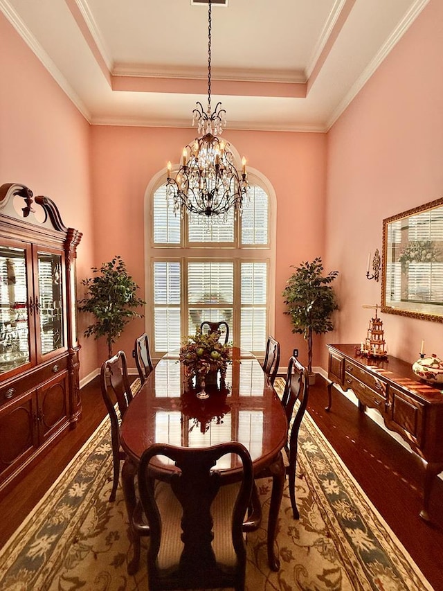 dining area with dark hardwood / wood-style floors, crown molding, and a tray ceiling