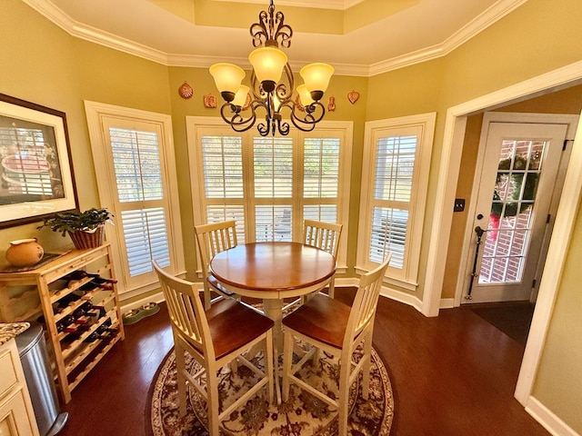 dining area with dark hardwood / wood-style floors, a raised ceiling, crown molding, and a chandelier