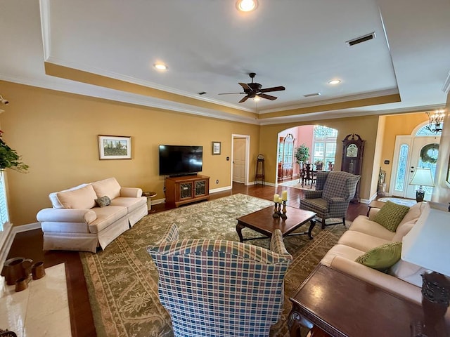 living room featuring hardwood / wood-style flooring, ceiling fan, a raised ceiling, and crown molding