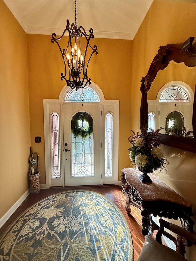 foyer entrance with crown molding, a notable chandelier, and hardwood / wood-style flooring