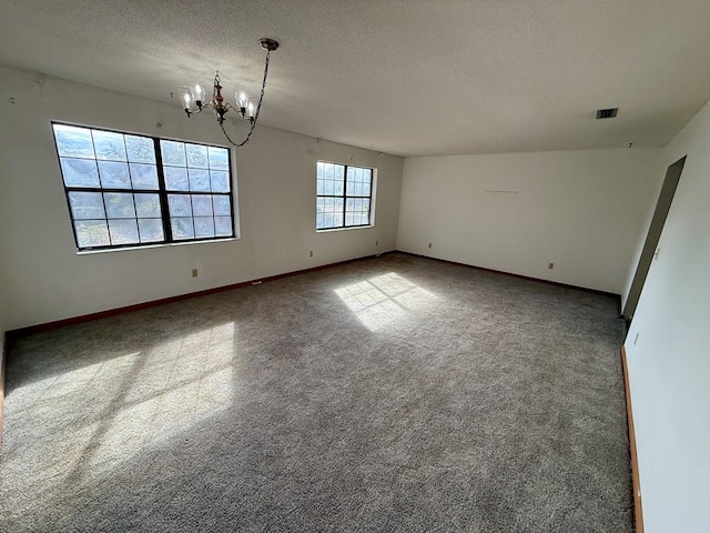 carpeted spare room featuring a textured ceiling and a notable chandelier