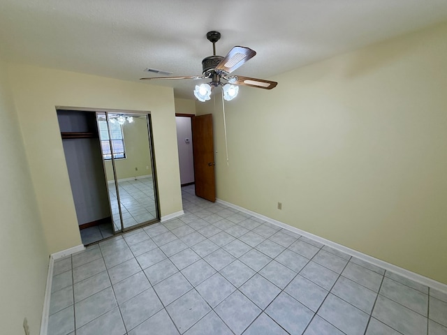 unfurnished bedroom with a textured ceiling, a closet, light tile patterned floors, and ceiling fan