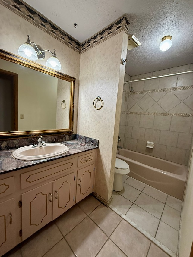 full bathroom with toilet, tiled shower / bath, tile patterned flooring, a textured ceiling, and vanity