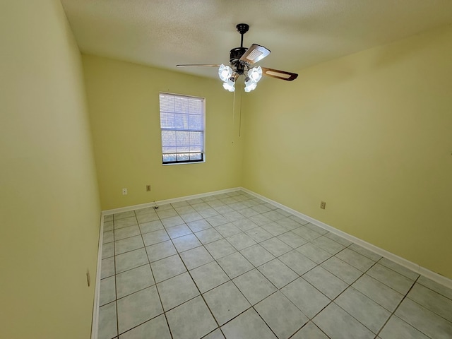 tiled empty room with ceiling fan and a textured ceiling