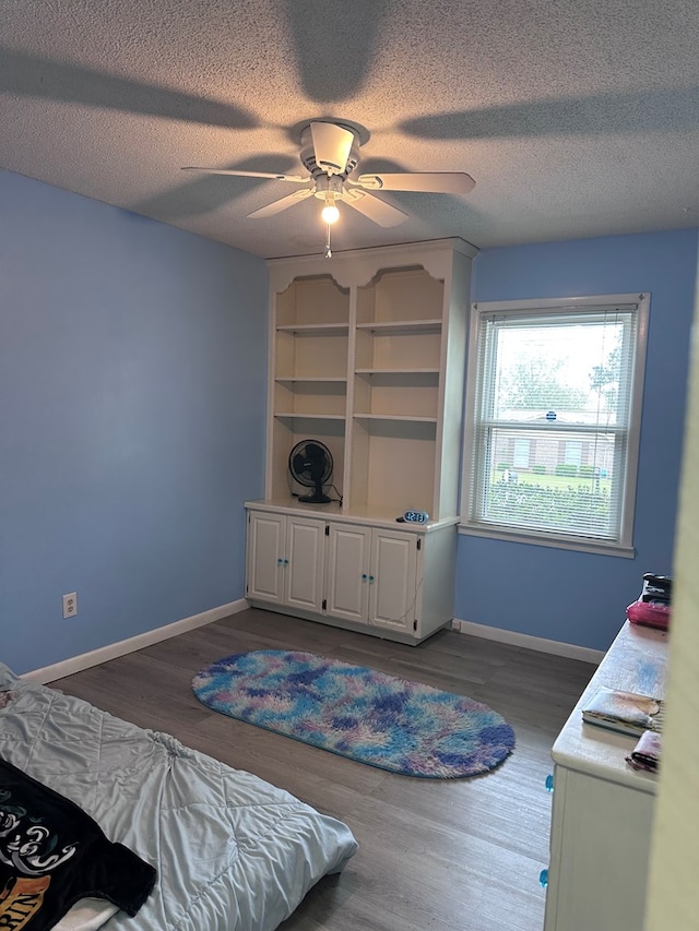 bedroom featuring a textured ceiling, baseboards, and wood finished floors