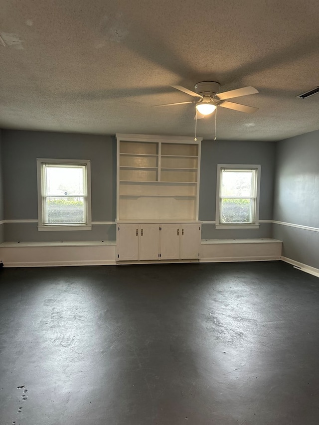 empty room with visible vents, a textured ceiling, finished concrete floors, and a ceiling fan