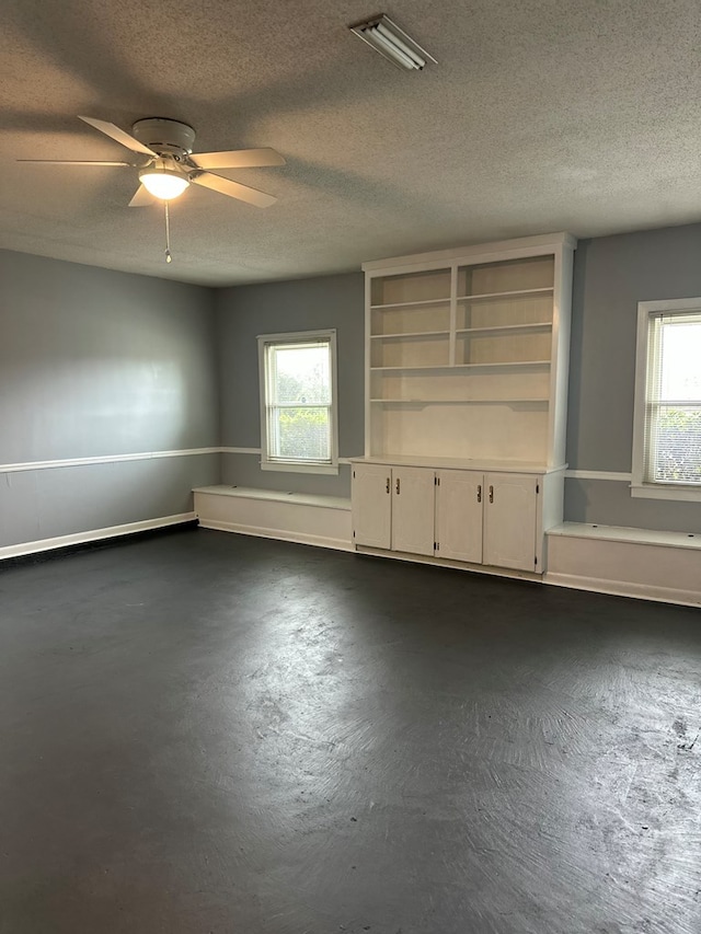 unfurnished room with a ceiling fan, a healthy amount of sunlight, visible vents, and concrete flooring