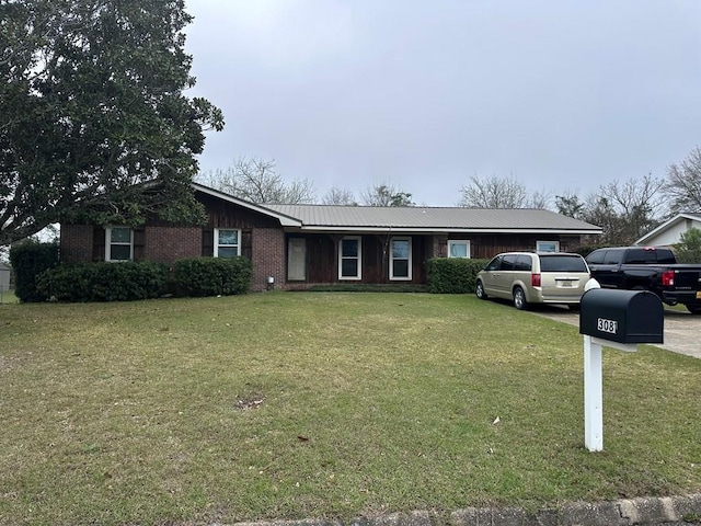 single story home featuring brick siding, concrete driveway, a front yard, and metal roof