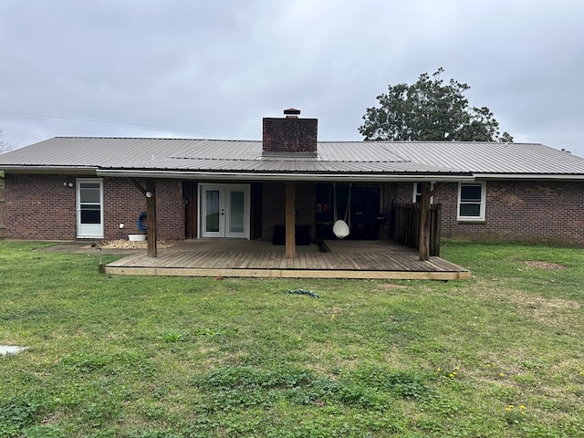 back of property featuring brick siding, a lawn, french doors, a chimney, and a deck