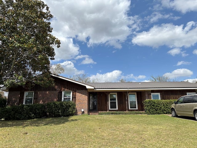 ranch-style home with metal roof, brick siding, and a front yard