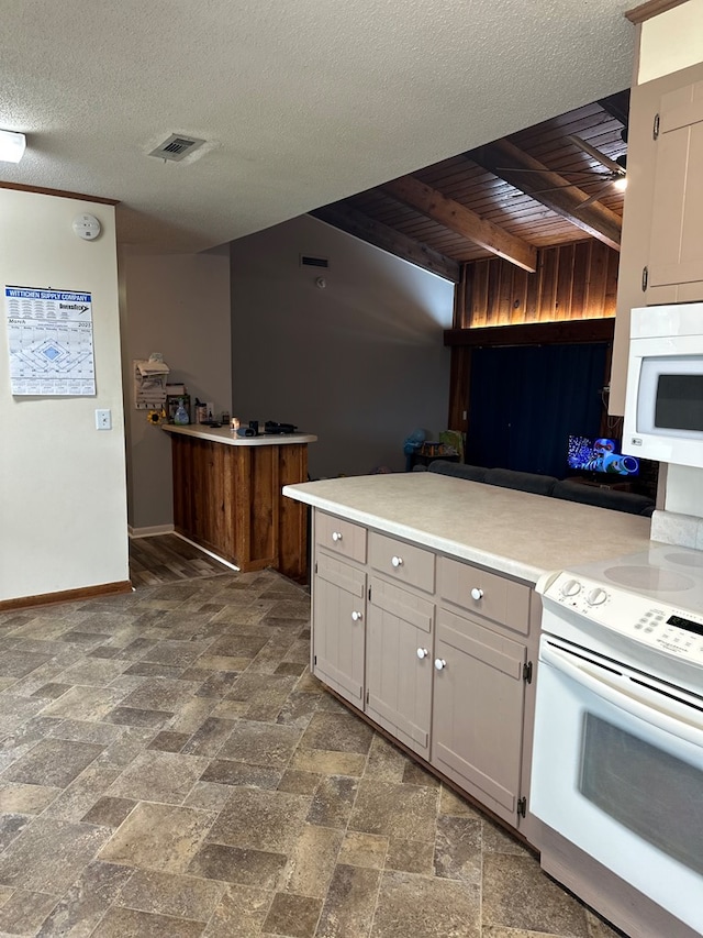 kitchen with baseboards, light countertops, a peninsula, white appliances, and a textured ceiling