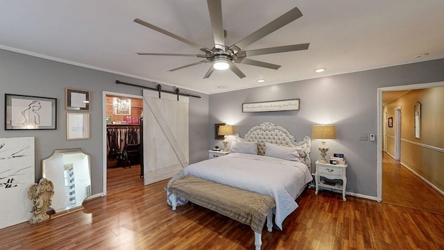 514 S Main St, Headland, AL 36345 - bedroom with a barn door, ornamental molding, a walk in closet, wood finished floors, and baseboards