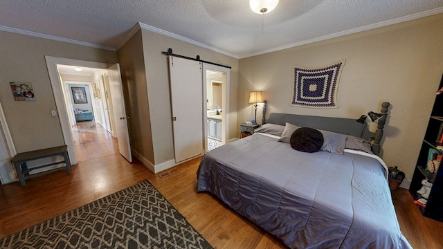 514 S Main St, Headland, AL 36345 - bedroom with a barn door, wood finished floors, a textured ceiling, crown molding, and baseboards