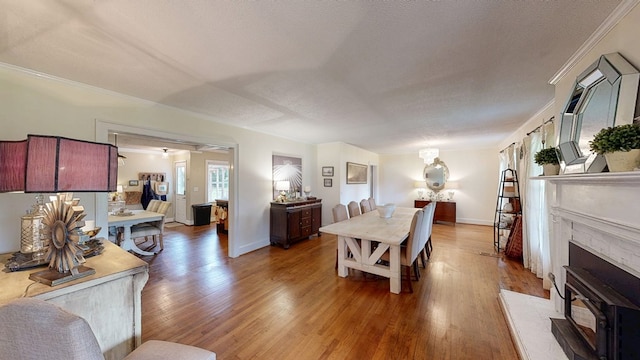 514 S Main St, Headland, AL 36345 - dining area featuring light wood finished floors, crown molding, a textured ceiling, baseboards, and a wood stove