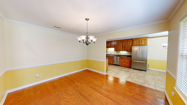 412 Darlington Cir, Dothan, AL 36301 - kitchen featuring appliances with stainless steel finishes, a chandelier, crown molding, decorative backsplash, and light wood-style floors
