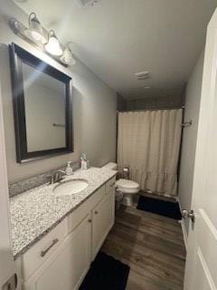 bathroom featuring wood-type flooring, toilet, vanity, and curtained shower