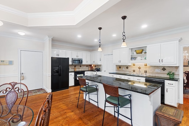 kitchen with a center island, white cabinets, black appliances, and hardwood / wood-style flooring