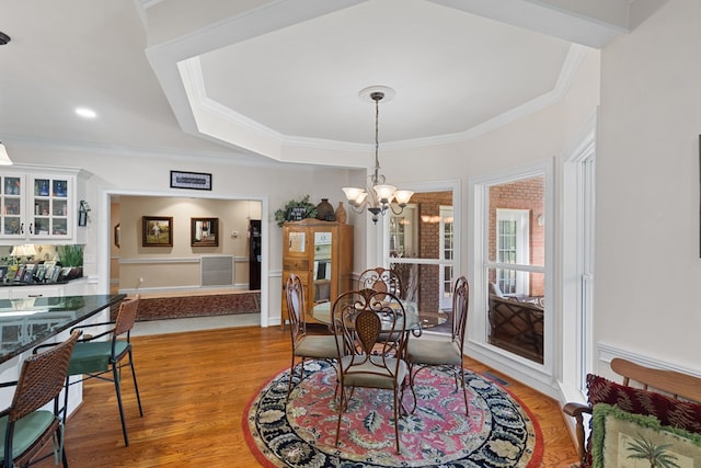 dining room with hardwood / wood-style flooring, an inviting chandelier, and crown molding