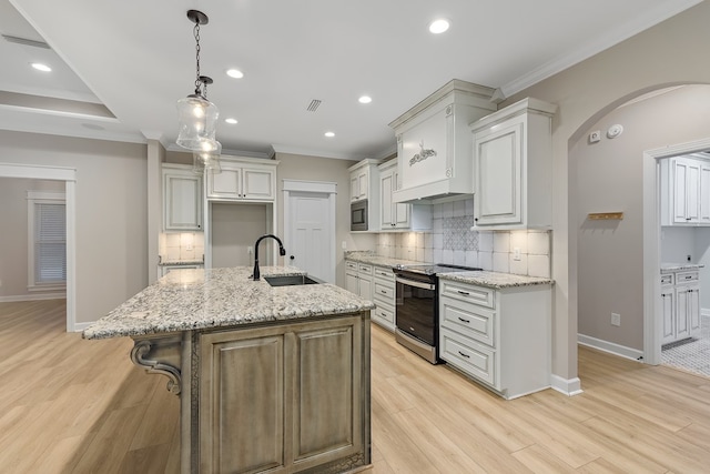 kitchen featuring white cabinets, electric range, sink, and an island with sink