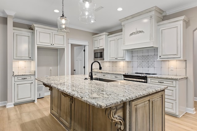 kitchen featuring white cabinets, sink, an island with sink, and appliances with stainless steel finishes