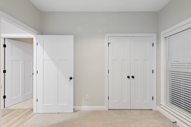 unfurnished bedroom with light carpet and a closet