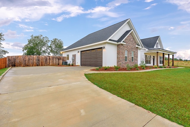 view of side of home featuring covered porch, a yard, and a garage