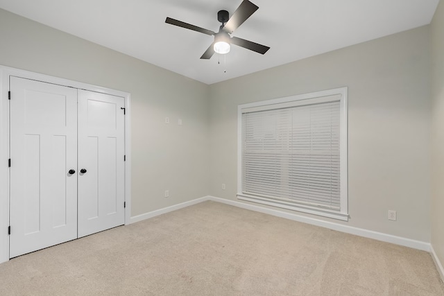 unfurnished bedroom with ceiling fan, a closet, and light carpet