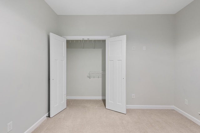 unfurnished bedroom featuring light colored carpet and a closet