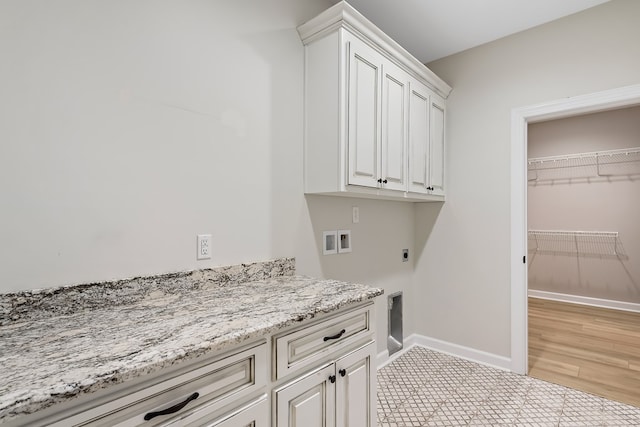 clothes washing area featuring cabinets, hookup for a washing machine, light hardwood / wood-style flooring, and electric dryer hookup