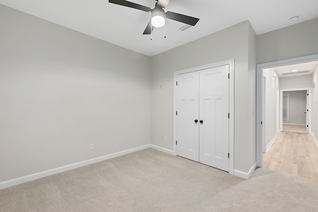 unfurnished bedroom featuring ceiling fan, a closet, and light colored carpet