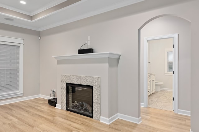 living room with light hardwood / wood-style floors, crown molding, and a tiled fireplace