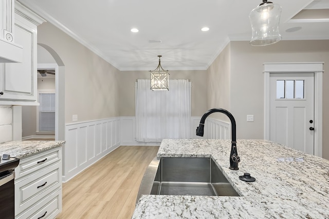 kitchen with hanging light fixtures, sink, white cabinets, and light hardwood / wood-style floors