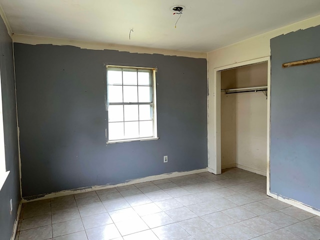 unfurnished bedroom with a closet, tile patterned floors, and baseboards