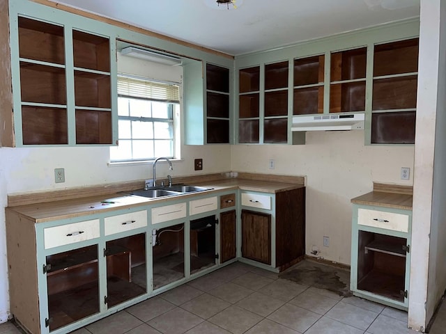 kitchen with light tile patterned flooring, open shelves, under cabinet range hood, and a sink