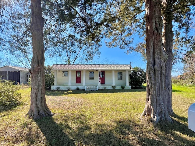 view of front facade with metal roof, covered porch, and a front yard