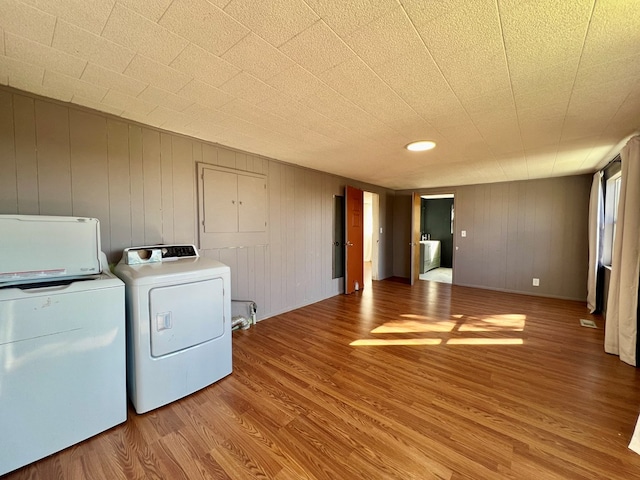 clothes washing area with laundry area, wood finished floors, and separate washer and dryer