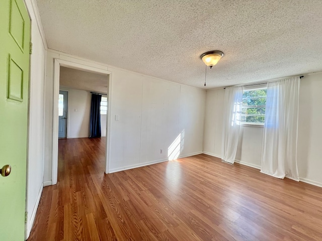 empty room featuring plenty of natural light, a textured ceiling, and wood finished floors