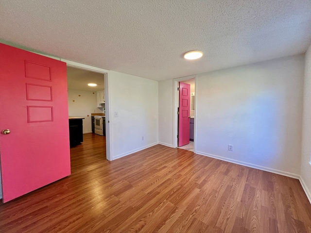unfurnished room with wood finished floors, baseboards, and a textured ceiling