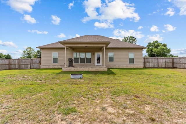back of property featuring a fenced backyard, a yard, and a shingled roof