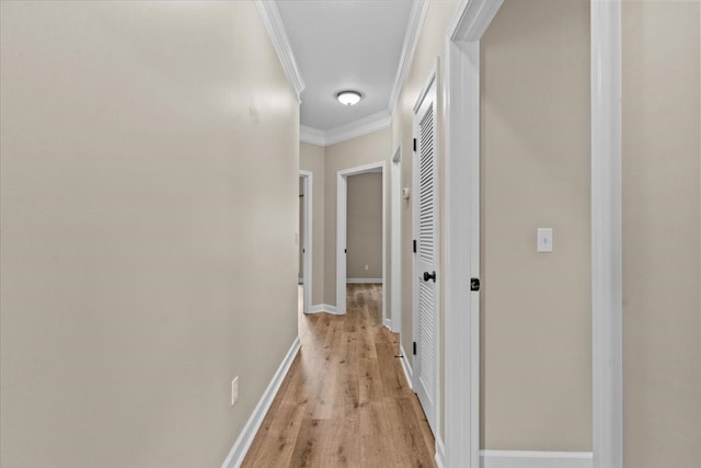 corridor with crown molding, baseboards, and light wood finished floors