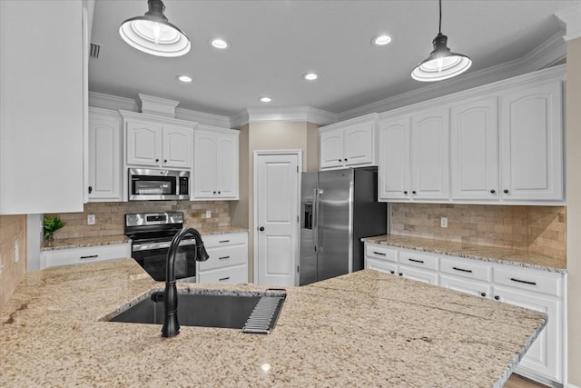 kitchen with crown molding, light stone countertops, white cabinetry, a sink, and stainless steel appliances