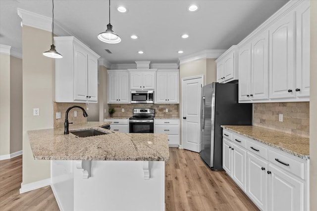 kitchen with a sink, appliances with stainless steel finishes, ornamental molding, and a peninsula