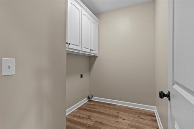laundry area with cabinet space, electric dryer hookup, baseboards, and light wood-type flooring