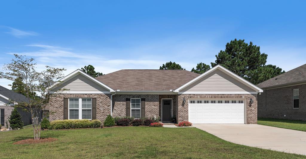 single story home featuring concrete driveway, a front lawn, an attached garage, and brick siding