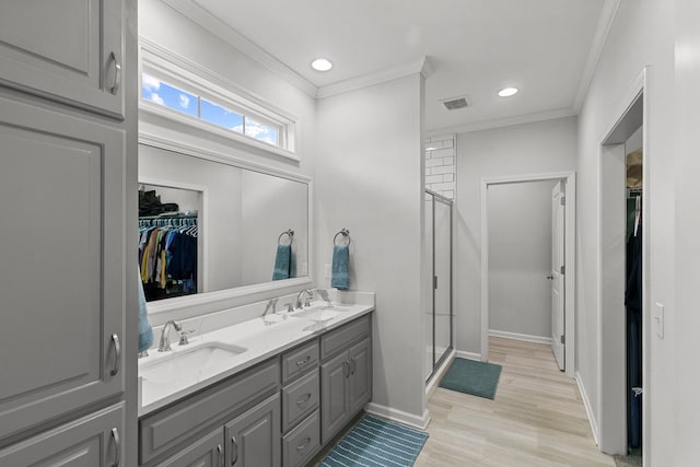 full bathroom featuring a sink, ornamental molding, a shower stall, and visible vents