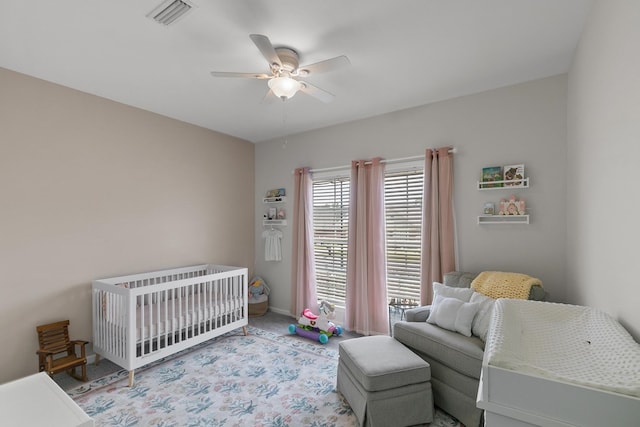 bedroom featuring visible vents, ceiling fan, carpet flooring, a crib, and baseboards